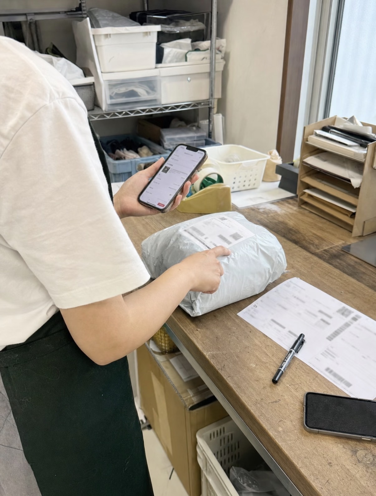 スマートフォンと伝票で出荷する荷物を確認する様子